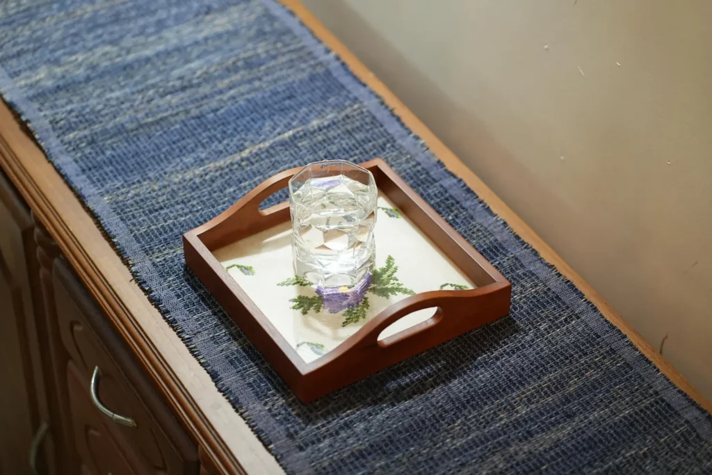 wooden tray with hand embroidered fabric at the base and acrylic sheet on top by a home decor store in kerala